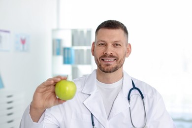 Photo of Nutritionist with green apple and stethoscope in clinic