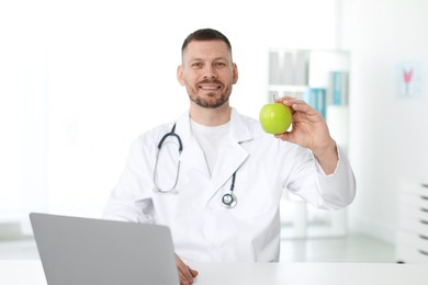 Photo of Nutritionist with green apple and stethoscope in clinic, selective focus