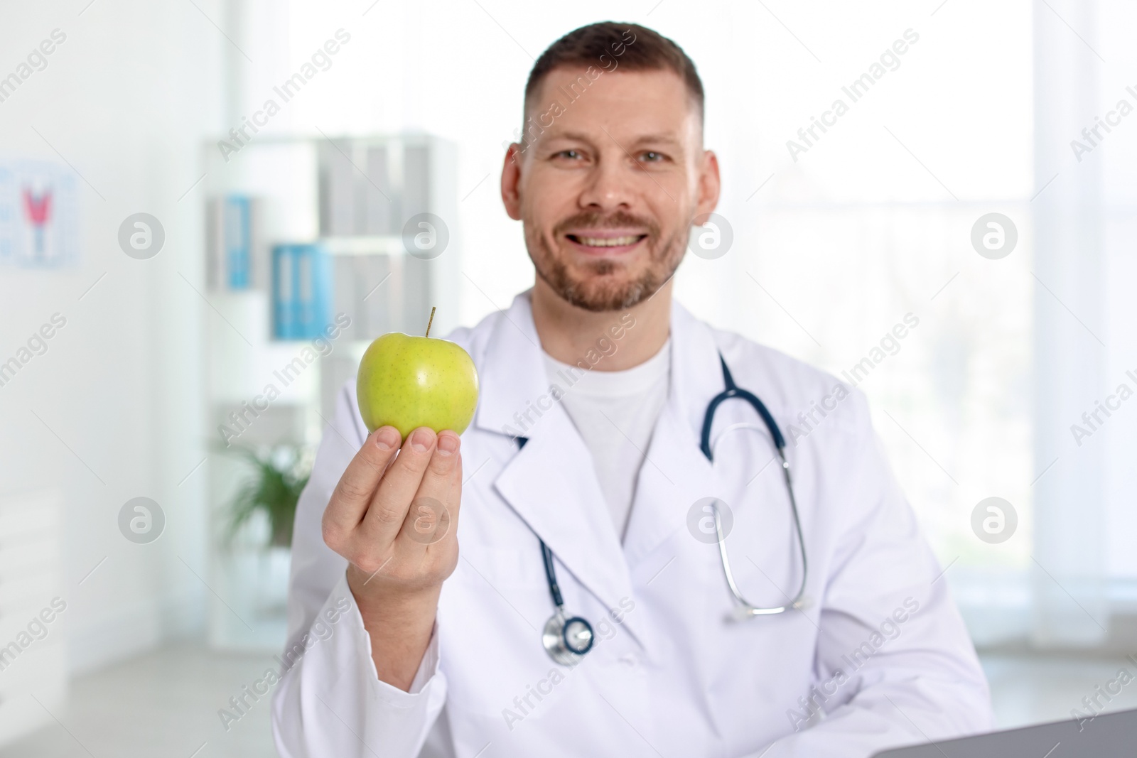 Photo of Nutritionist with green apple and stethoscope in clinic