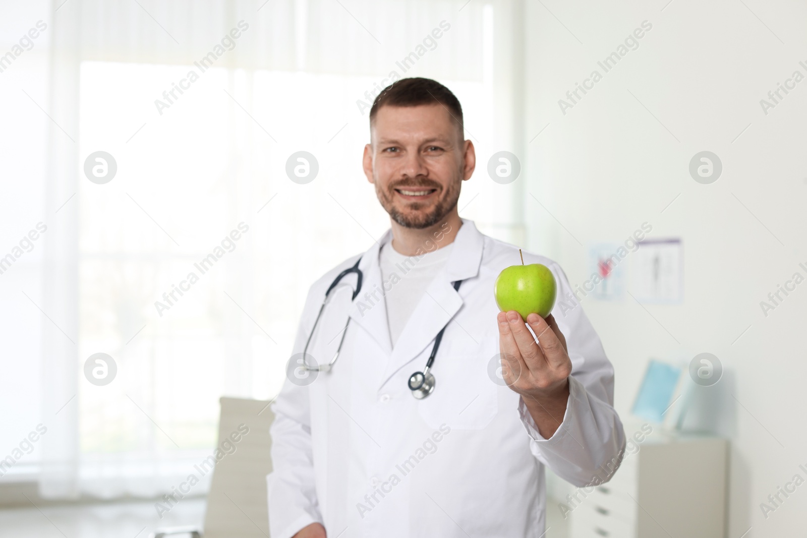 Photo of Nutritionist with green apple and stethoscope in clinic
