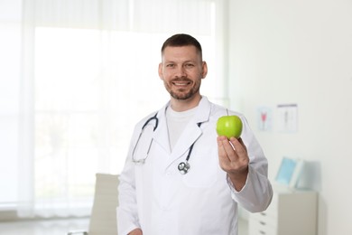 Photo of Nutritionist with green apple and stethoscope in clinic