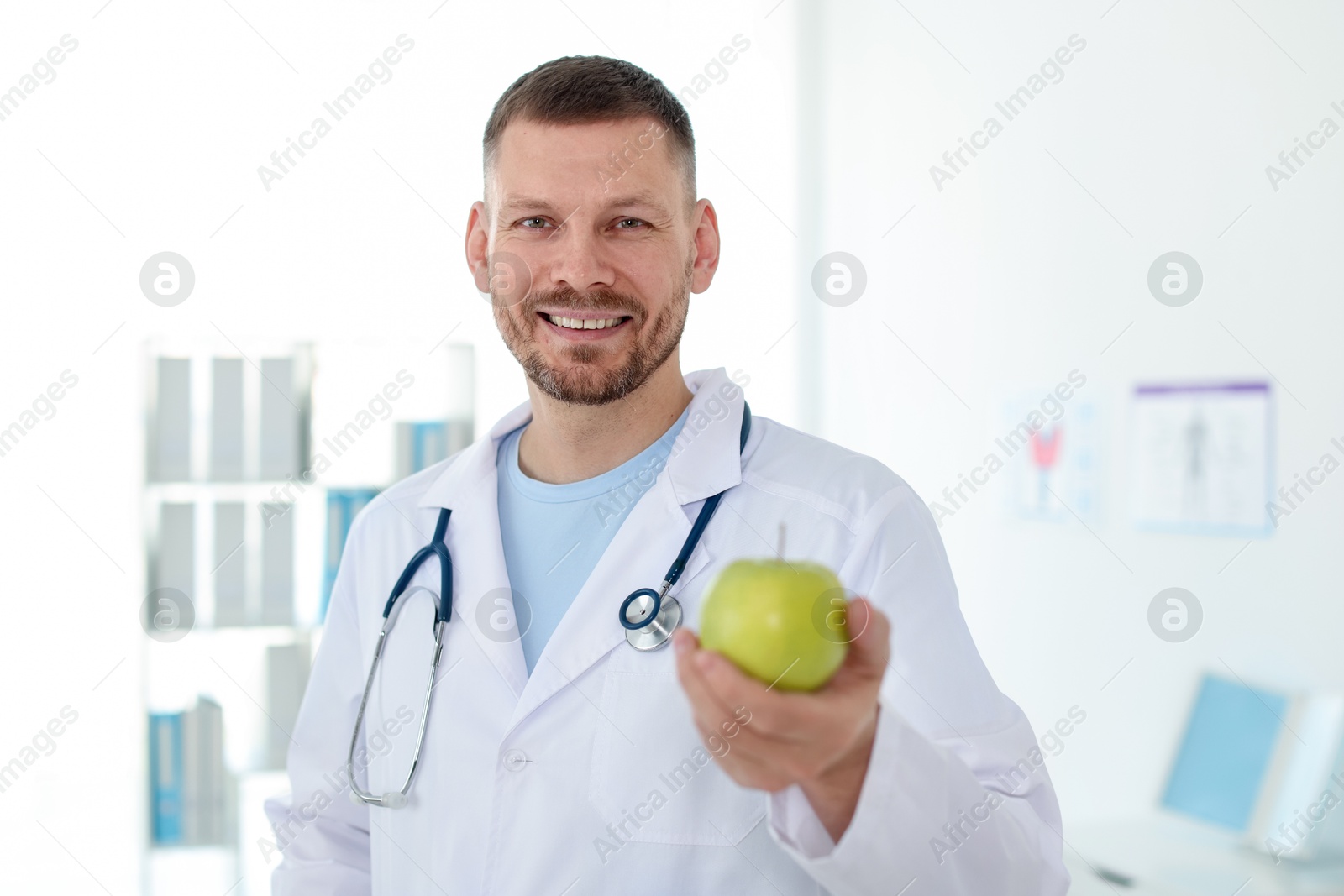 Photo of Nutritionist with green apple and stethoscope in clinic