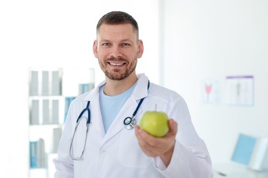 Photo of Nutritionist with green apple and stethoscope in clinic