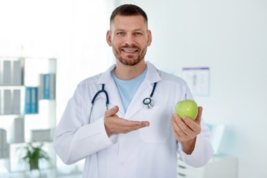 Photo of Nutritionist with green apple and stethoscope in clinic