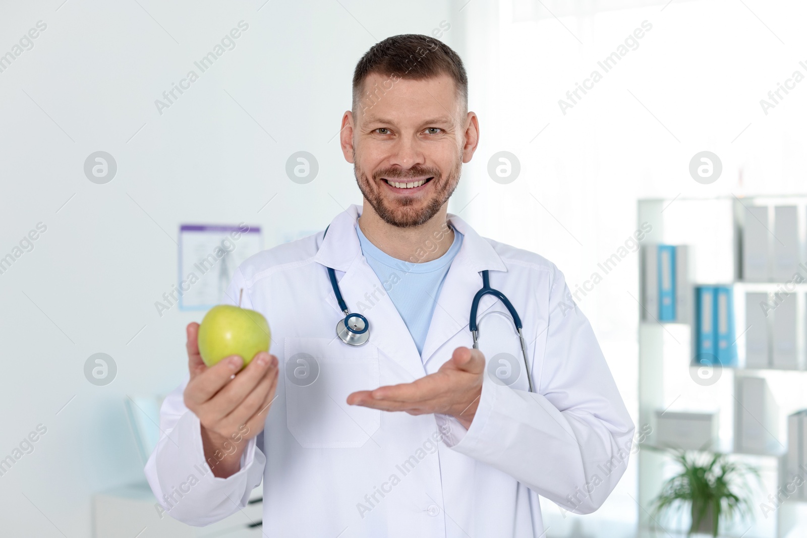 Photo of Nutritionist with green apple and stethoscope in clinic