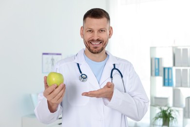 Photo of Nutritionist with green apple and stethoscope in clinic