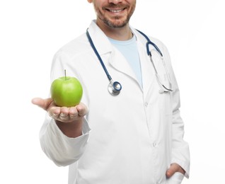 Photo of Nutritionist with green apple and stethoscope on white background, closeup