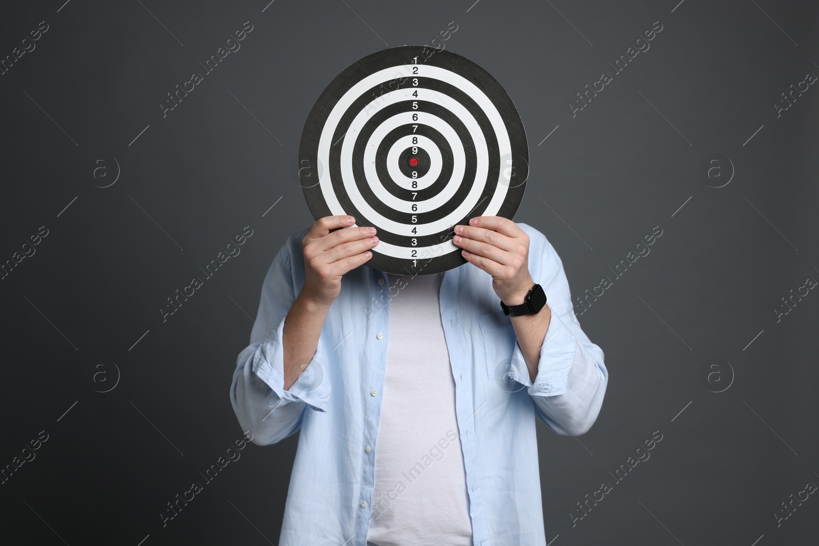 Targeting. Man with dart board on grey background Photo of Targeting. Man with dart board on grey background