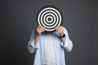 Photo of Targeting. Man with dart board on grey background