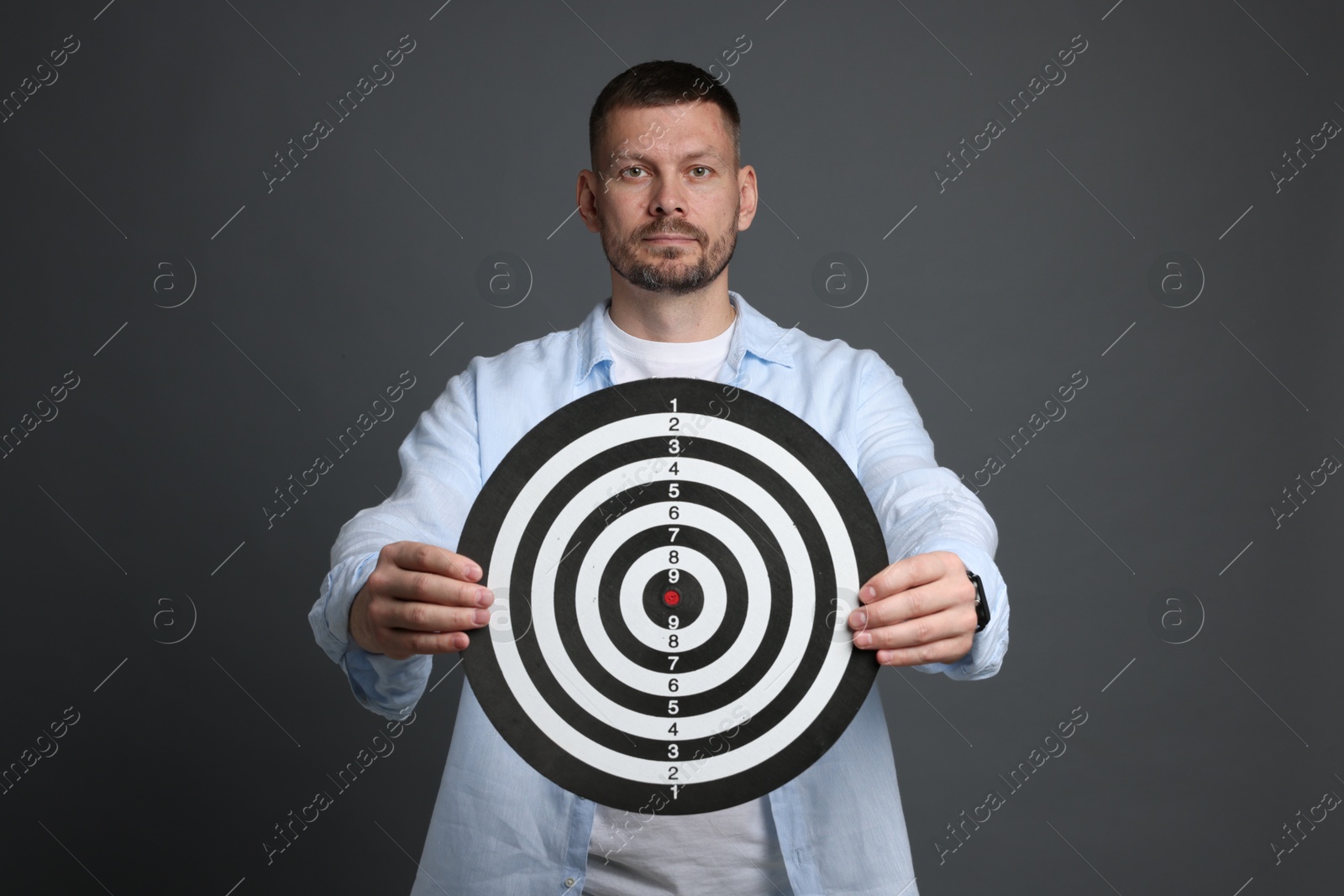 Targeting. Man with dart board on grey background Photo of Targeting. Man with dart board on grey background