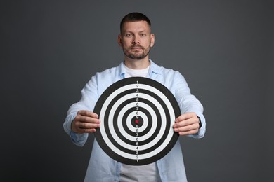Photo of Targeting. Man with dart board on grey background