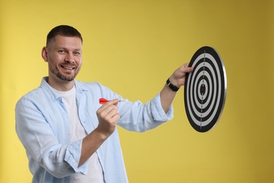 Photo of Targeting. Man with dart board and arrow on yellow background