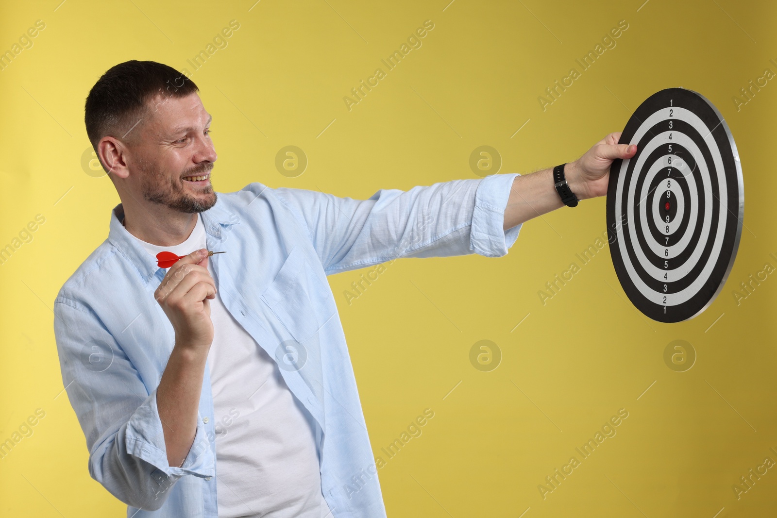 Targeting. Man with dart board and arrow on yellow background Photo of Targeting. Man with dart board and arrow on yellow background