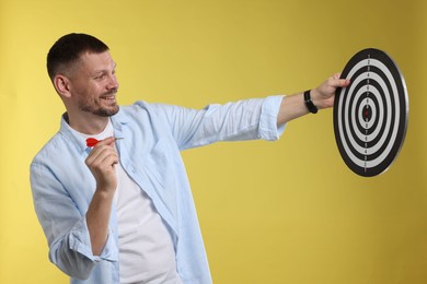 Photo of Targeting. Man with dart board and arrow on yellow background