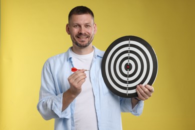 Photo of Targeting. Man with dart board and arrow on yellow background