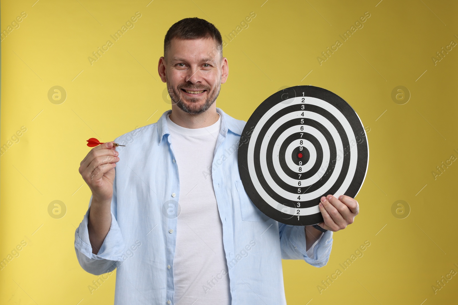 Targeting. Man with dart board and arrow on yellow background Photo of Targeting. Man with dart board and arrow on yellow background