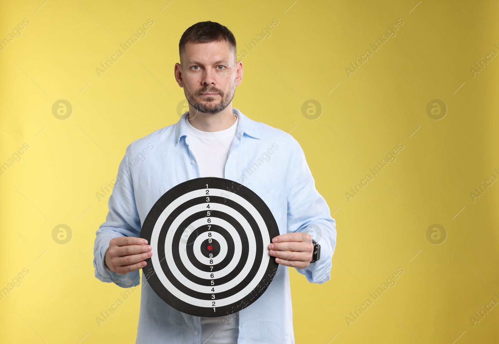 Targeting. Man with dart board on yellow background Photo of Targeting. Man with dart board on yellow background