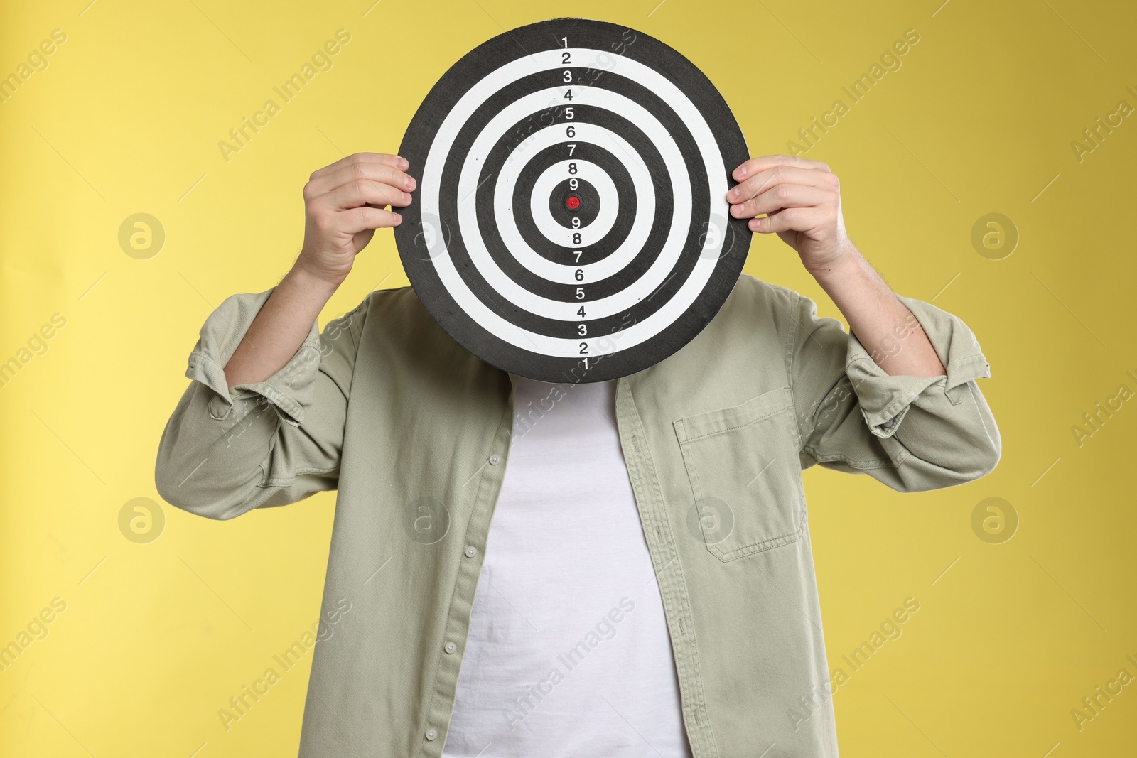 Targeting. Man with dart board on yellow background Photo of Targeting. Man with dart board on yellow background