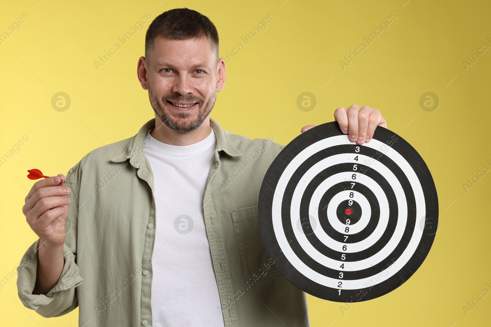 Targeting. Man with dart board and arrow on yellow background Photo of Targeting. Man with dart board and arrow on yellow background