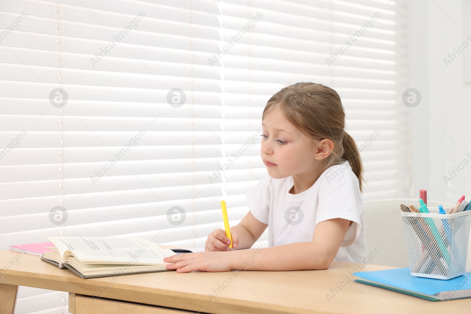 Little girl doing homework at table indoors Photo of Little girl doing homework at table indoors
