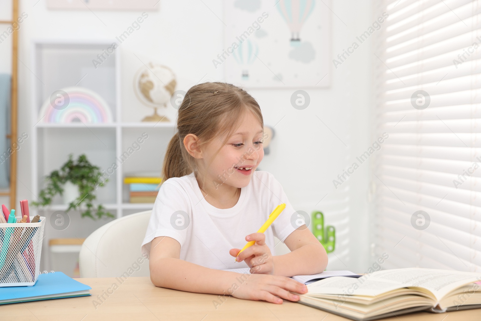 Little girl doing homework at table indoors Photo of Little girl doing homework at table indoors