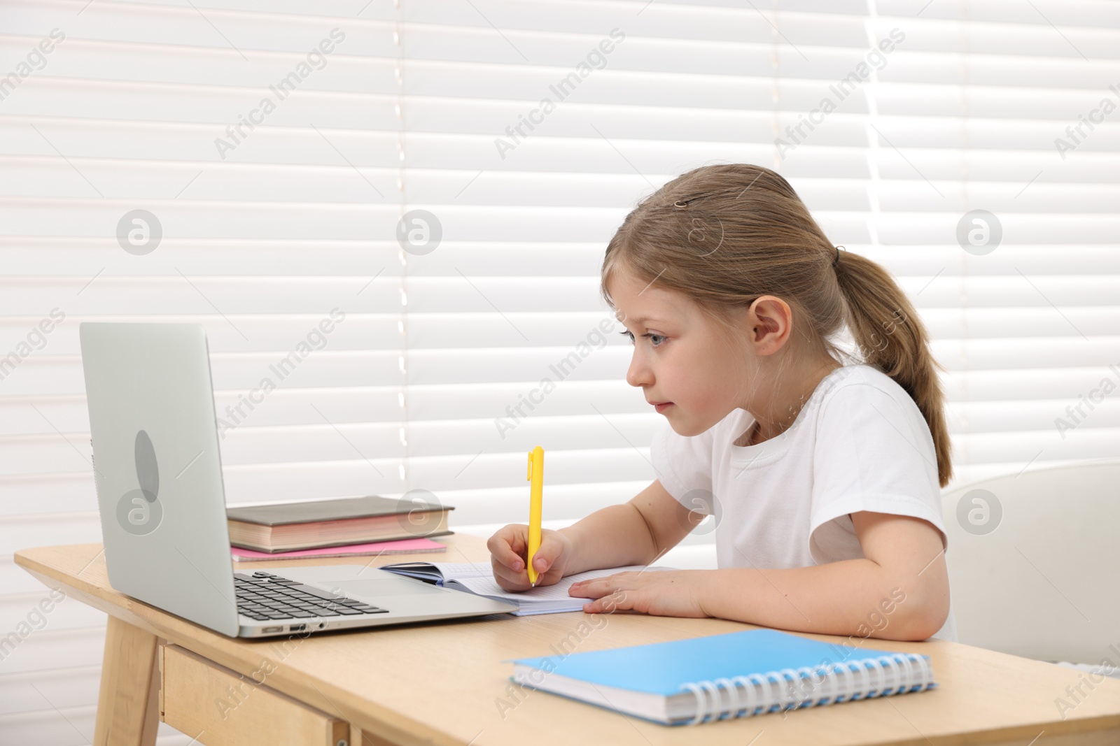 Little girl doing homework at table indoors Photo of Little girl doing homework at table indoors