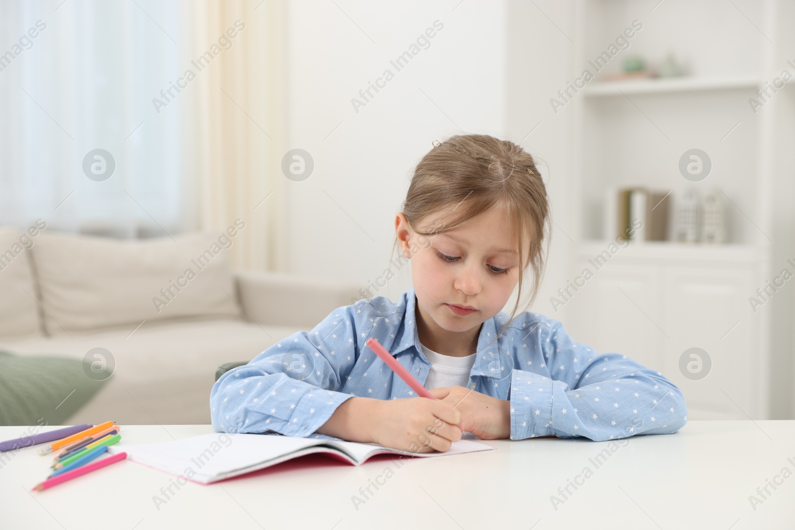 Little girl doing homework at table indoors Photo of Little girl doing homework at table indoors