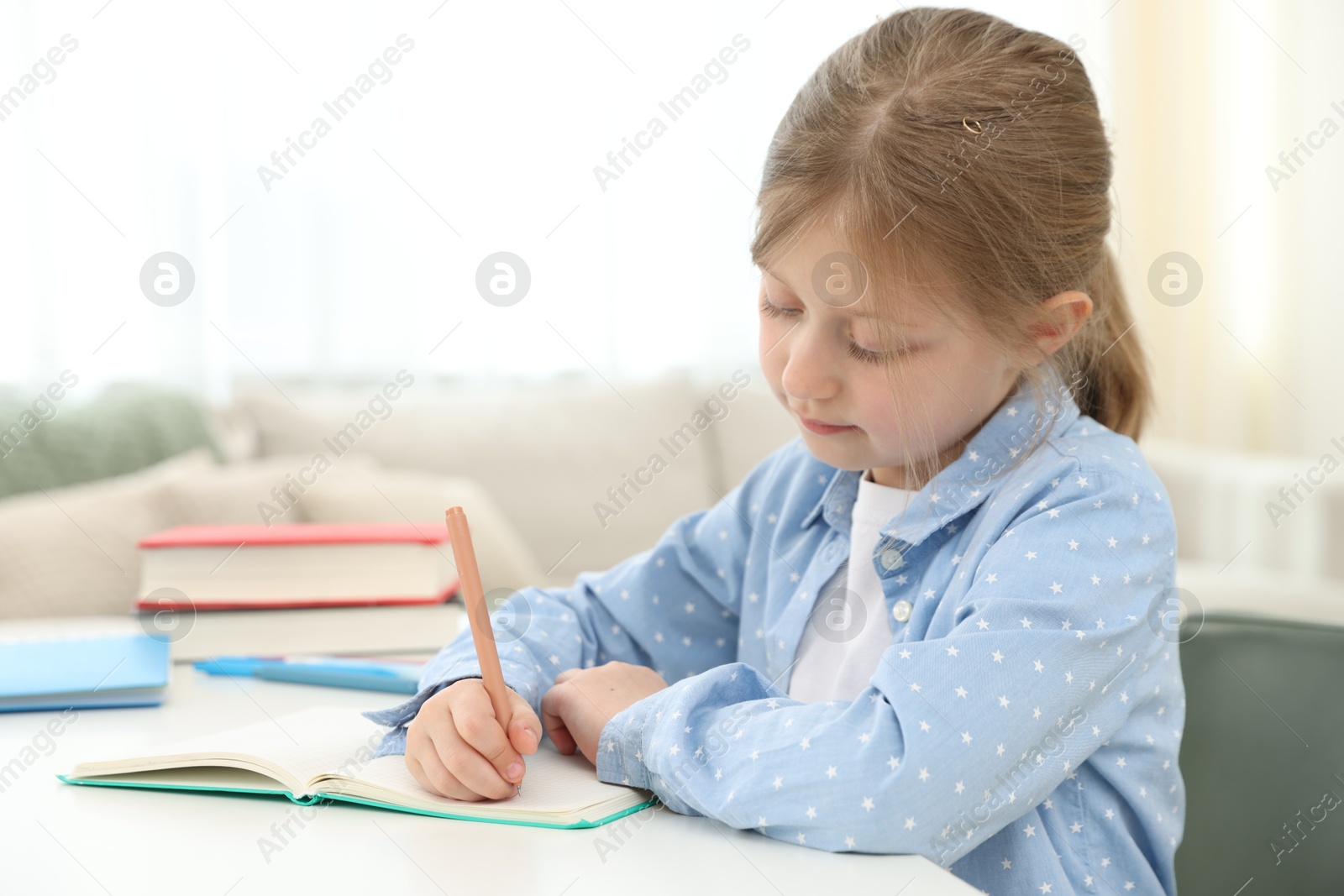 Little girl doing homework at table indoors Photo of Little girl doing homework at table indoors