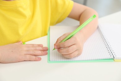 Photo of Little girl doing homework at table indoors, closeup