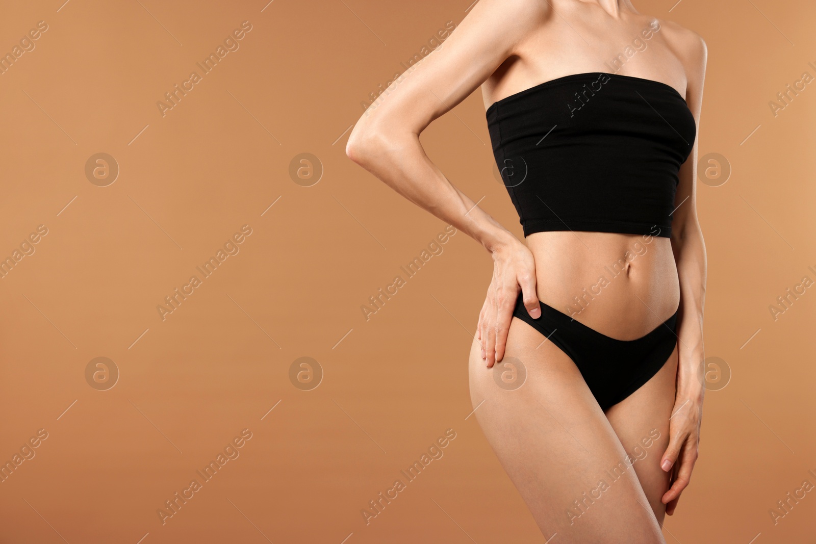 Photo of Woman with perfect slim body on beige background, closeup. Space for text