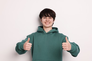 Photo of Portrait of teenage boy showing thumbs up on white background