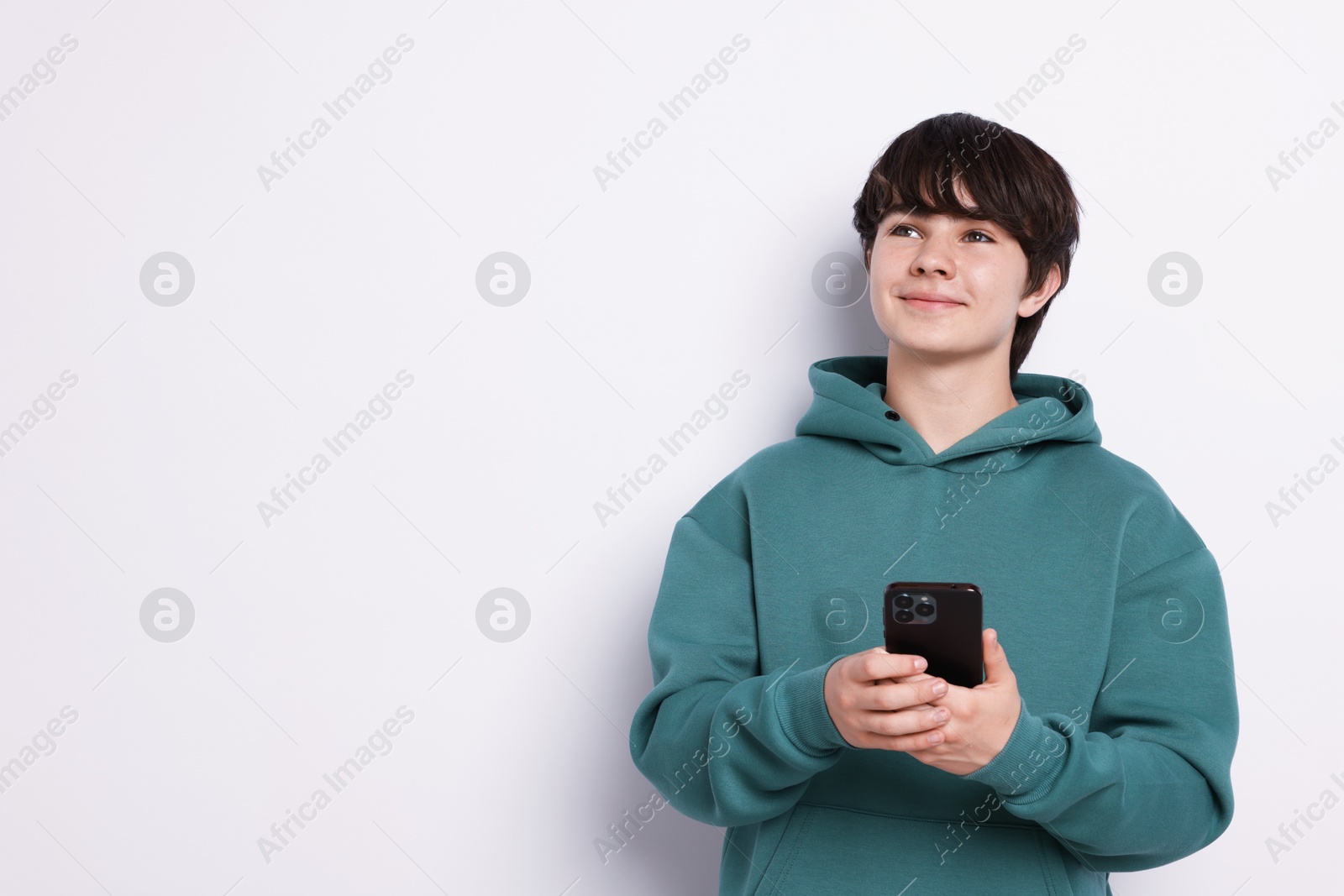 Teenage boy with smartphone on white background, space for text Photo of Teenage boy with smartphone on white background, space for text