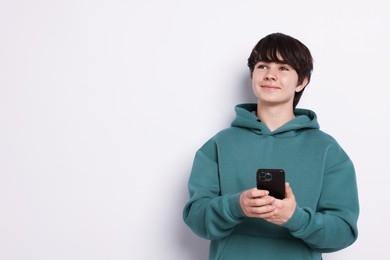 Photo of Teenage boy with smartphone on white background, space for text