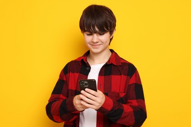 Photo of Teenage boy with smartphone on orange background