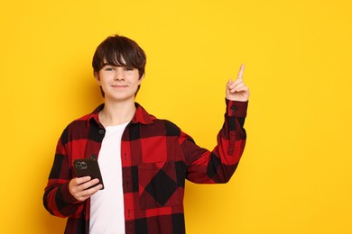 Photo of Teenage boy with smartphone on orange background, space for text