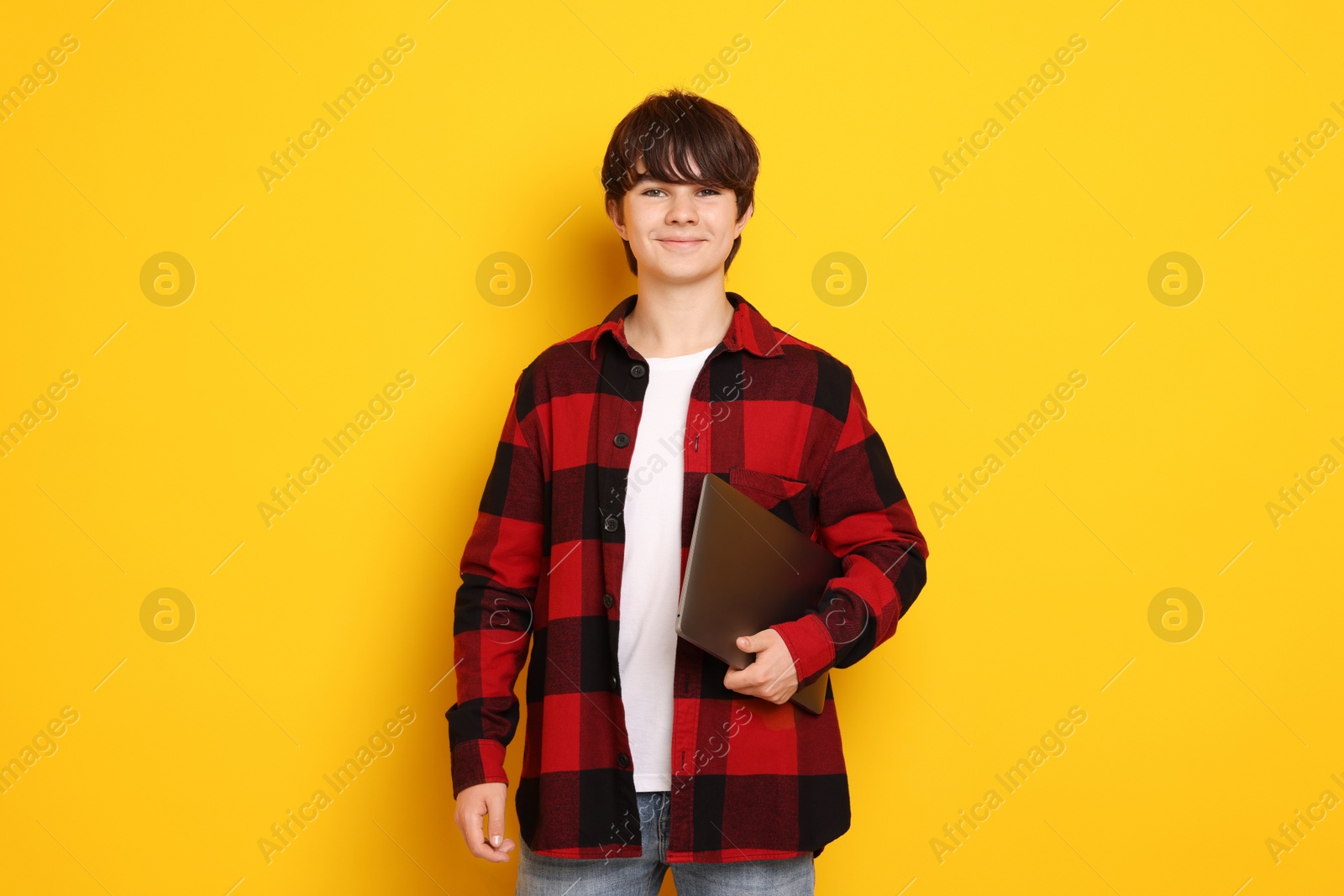 Photo of Teenage boy with laptop on orange background
