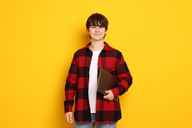 Photo of Teenage boy with laptop on orange background