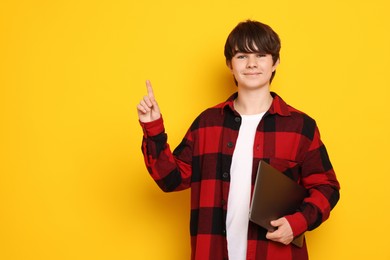 Photo of Teenage boy with laptop on orange background, space for text