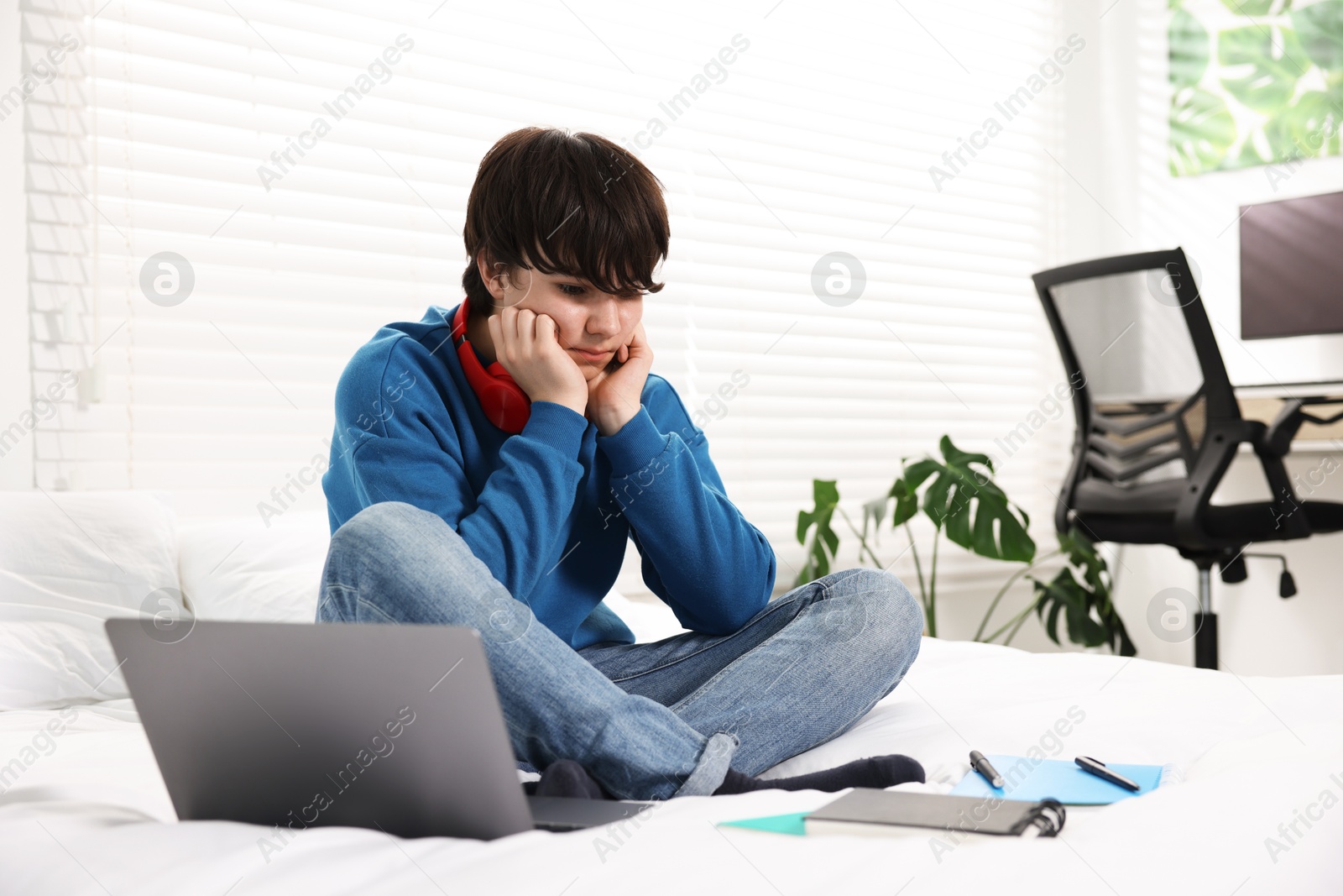 Photo of Teenage boy doing homework on bed indoors