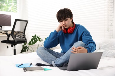 Photo of Teenage boy doing homework on bed indoors