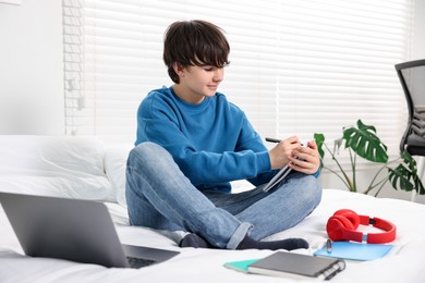 Photo of Teenage boy doing homework on bed indoors