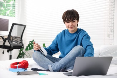 Photo of Teenage boy doing homework on bed indoors