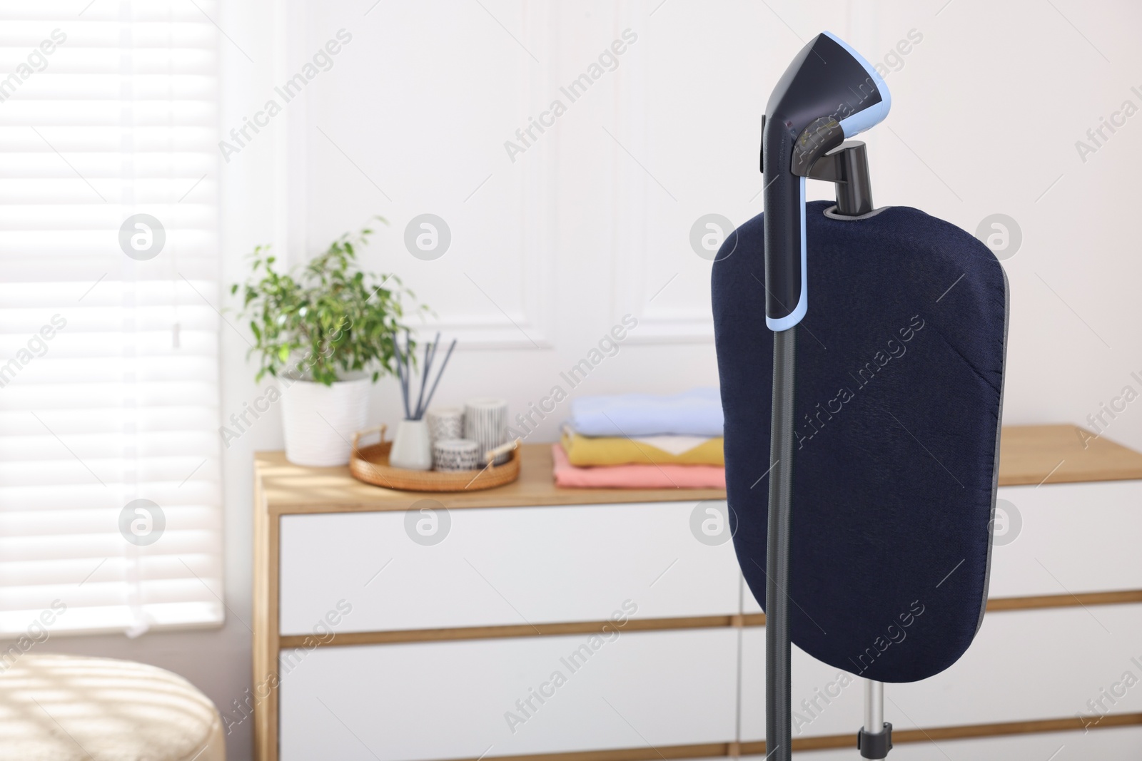 Modern upright steamer indoors, closeup. Space for text Photo of Modern upright steamer indoors, closeup. Space for text