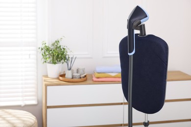 Photo of Modern upright steamer indoors, closeup. Space for text
