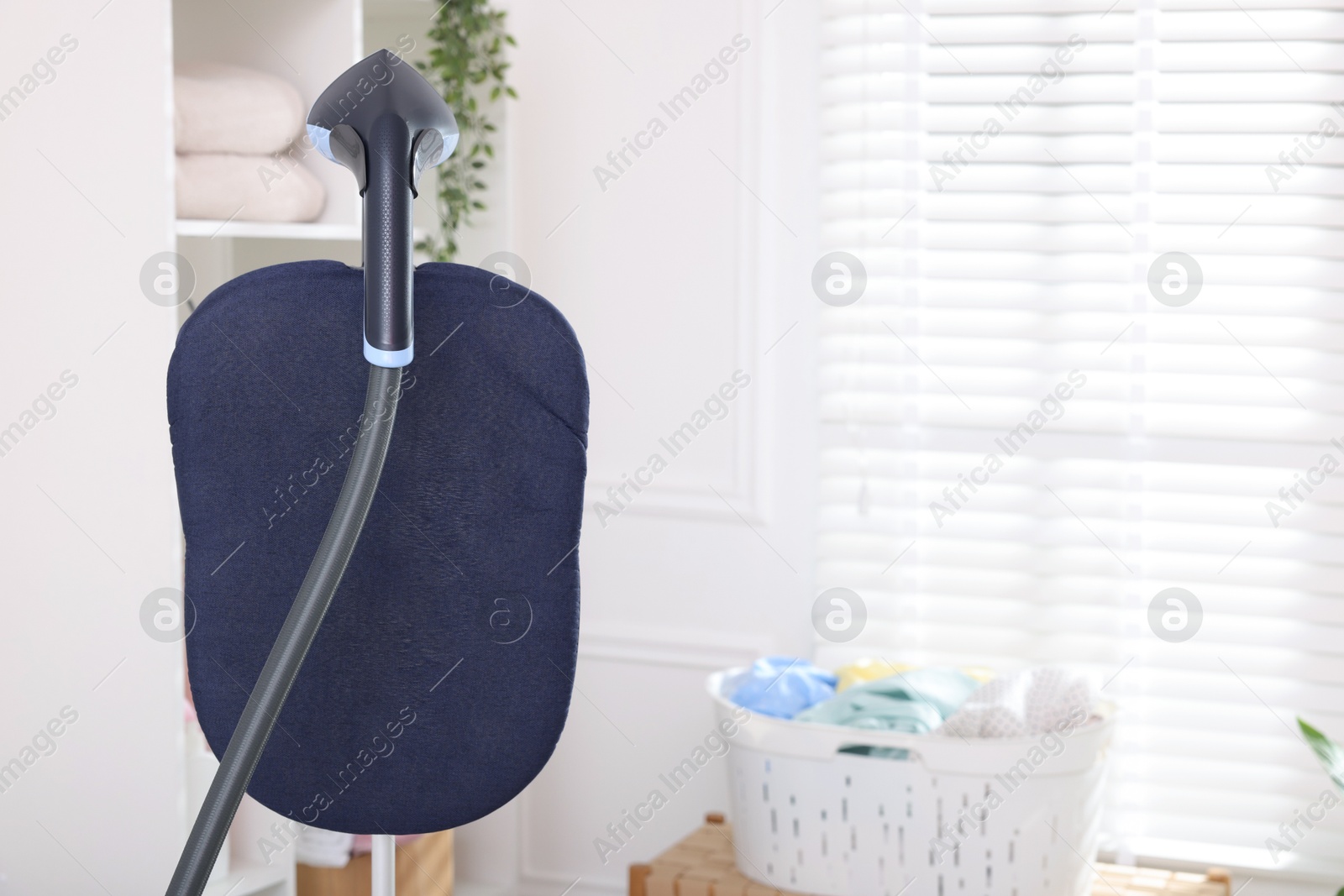 Modern upright steamer indoors, closeup. Space for text Photo of Modern upright steamer indoors, closeup. Space for text