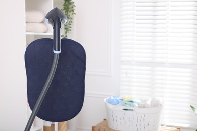 Photo of Modern upright steamer indoors, closeup. Space for text