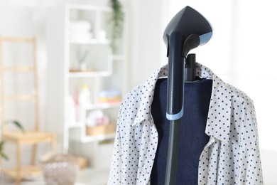 Photo of Modern upright steamer and shirt indoors. Space for text