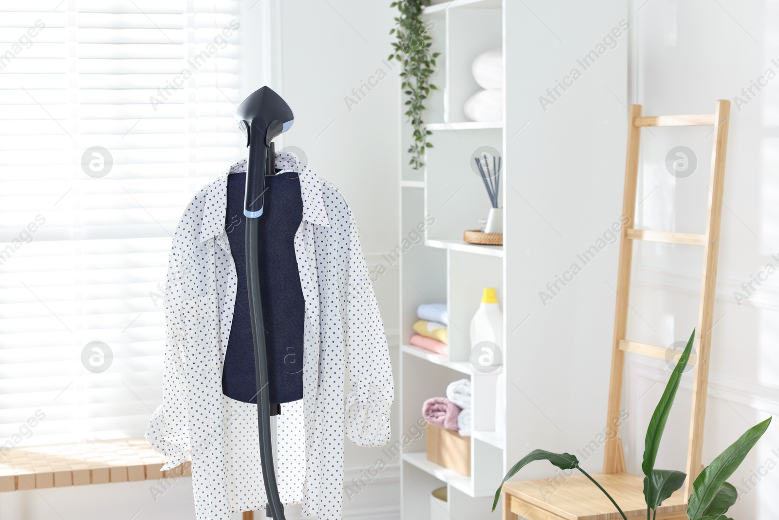 Modern upright steamer and shirt indoors. Space for text Photo of Modern upright steamer and shirt indoors. Space for text