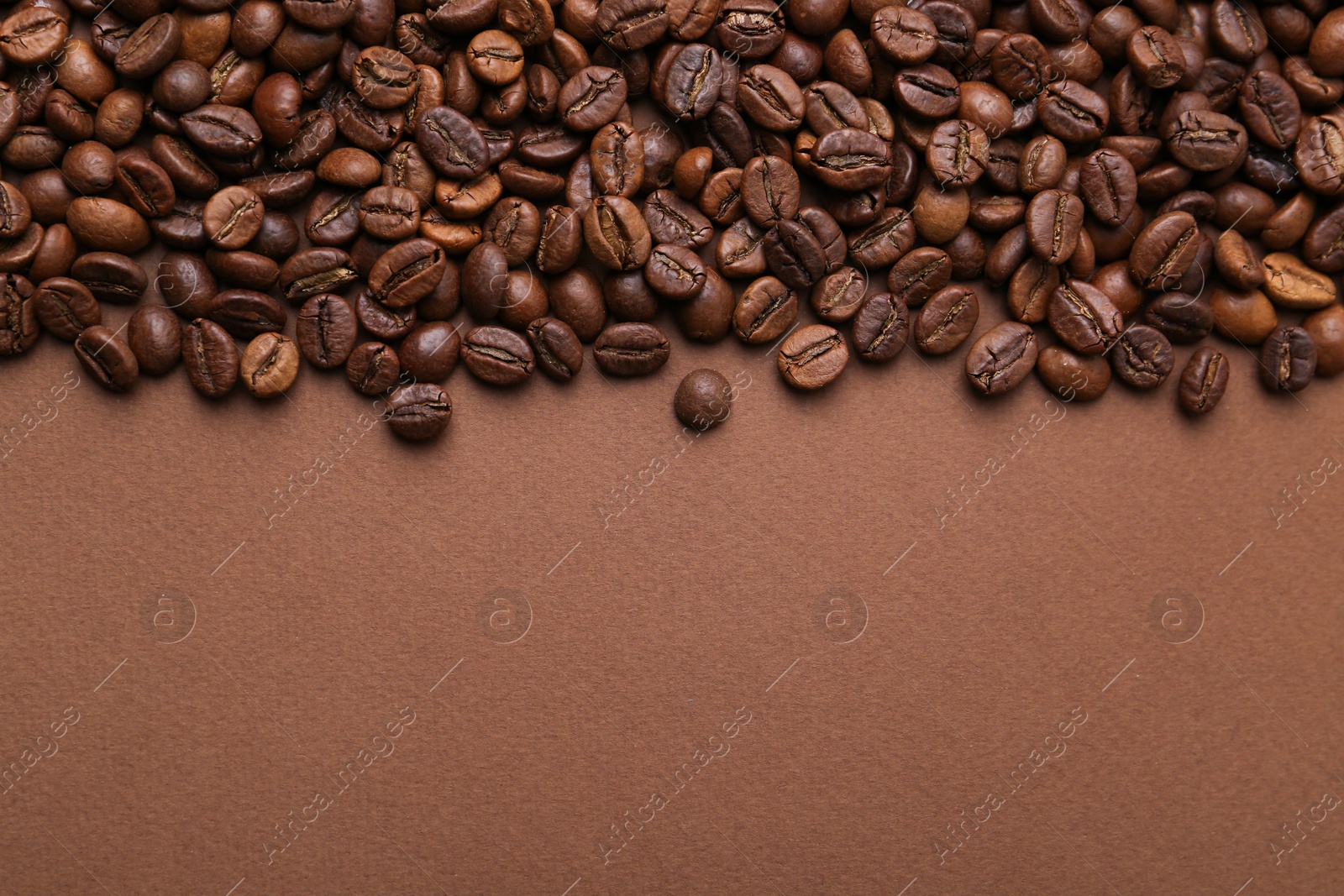 Aromatic coffee beans on brown background, top view. Space for text Photo of Aromatic coffee beans on brown background, top view. Space for text