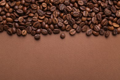 Photo of Aromatic coffee beans on brown background, top view. Space for text